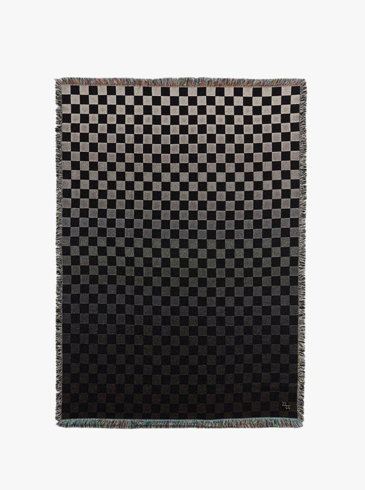 The Iki Cotton Jacquard Throw by 2222Studio features a black and gray checkerboard pattern with small gradient squares fading from light to dark, finished with fringed edges.