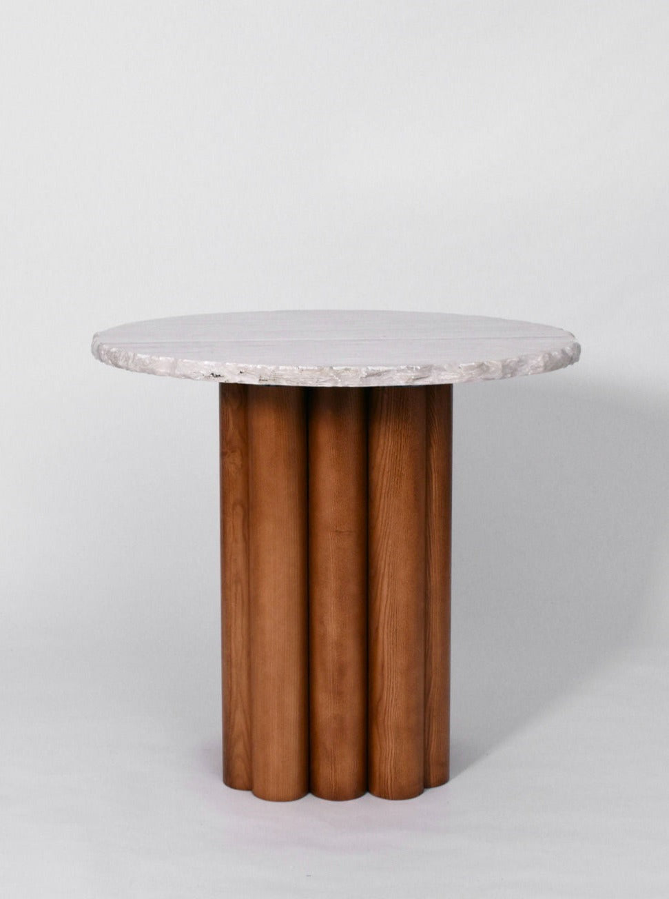 The Carrasqueira Table by Barracuda Interiors features a modern round white marble top and four vertical wooden pillar legs, presented against a plain light gray background.
