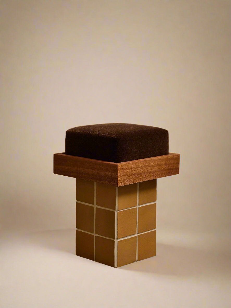 Modern geometric stool with dark cushion and golden cube base