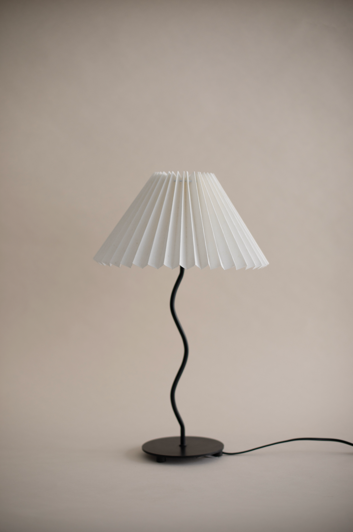Modern table lamp with white pleated shade and curved black stem