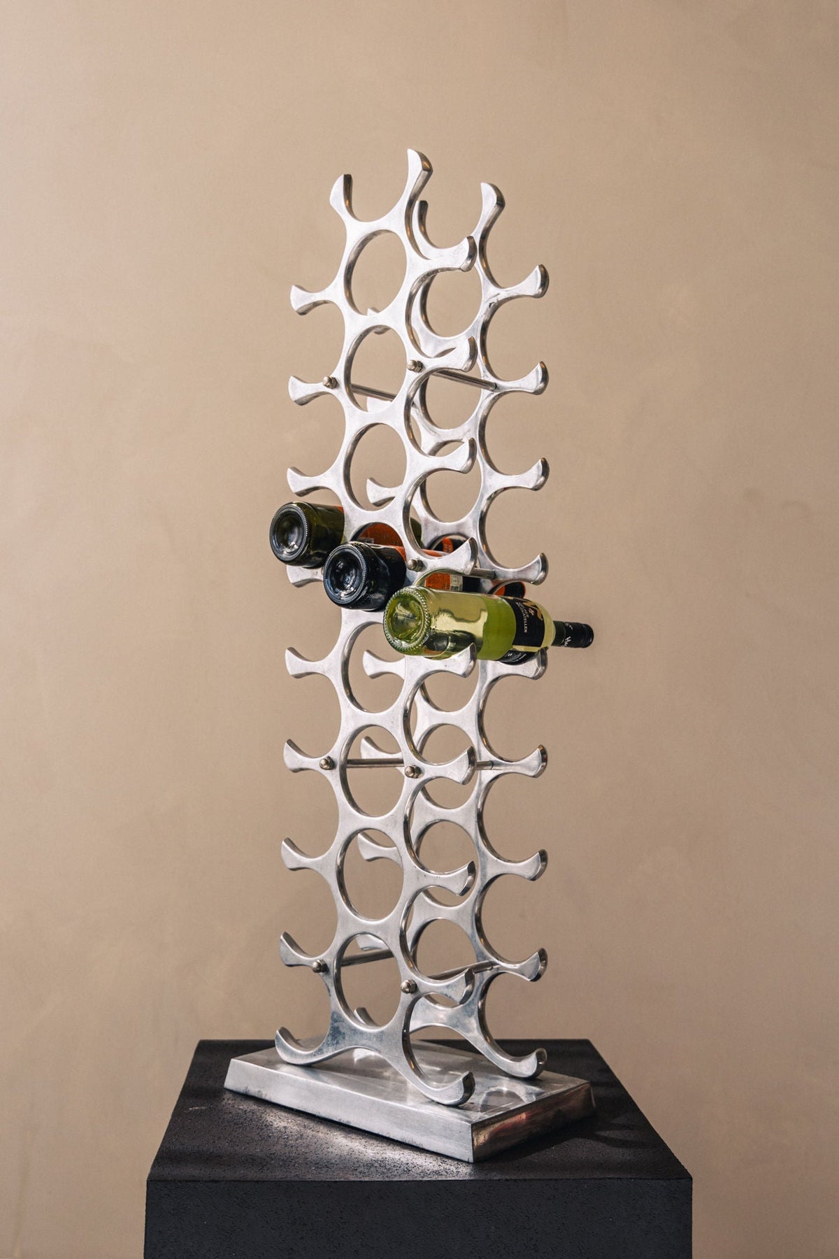 Modern aluminum wine rack with sculptural design holding wine bottles