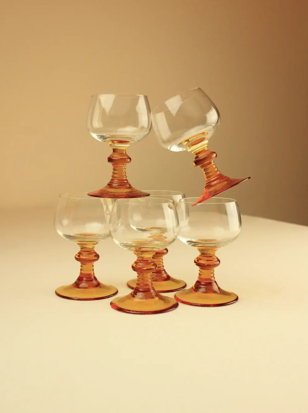 Set of six Roemer glasses in clear crystal with green stems and gold accents on a white background