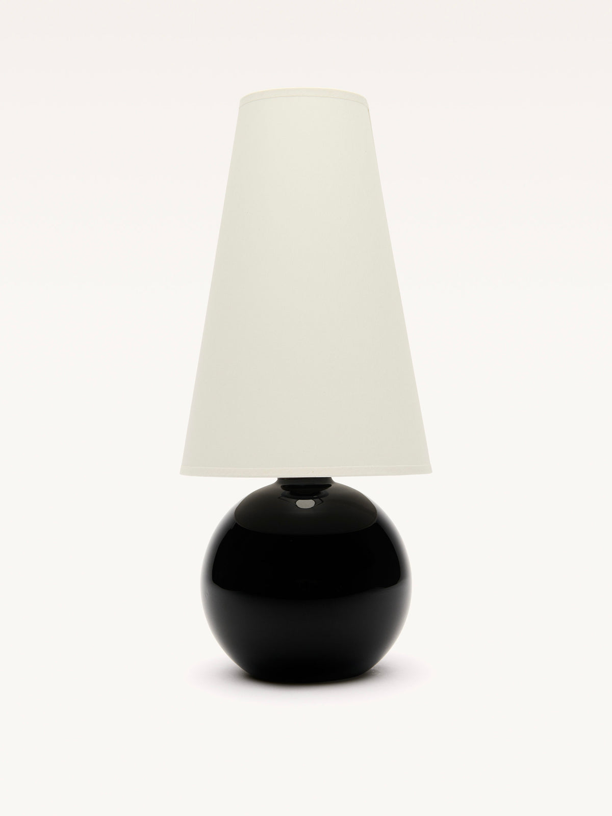 The Large Black Opalin Glass Lamp by Galerie MLS has a sleek black spherical base and a tall white cylindrical shade. A subtle brass ring adds to its modern design, making it a striking centerpiece against a white background.