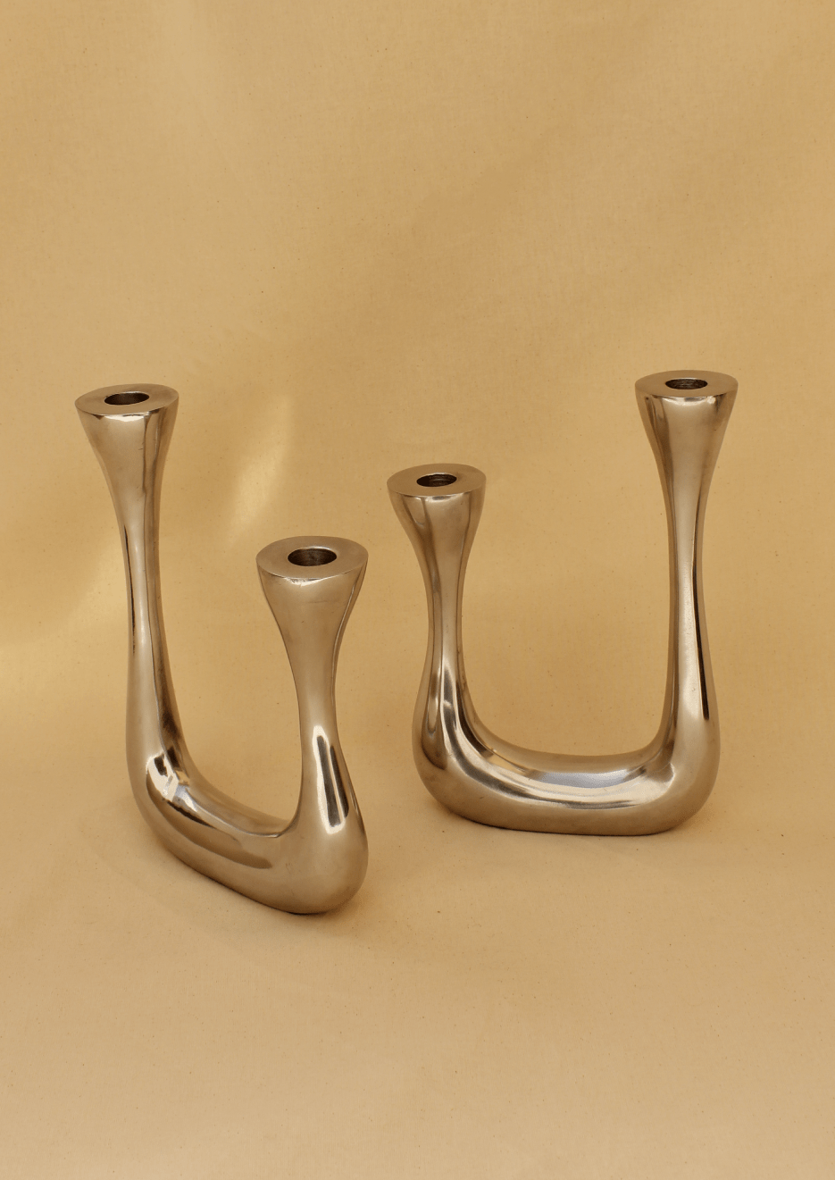 Three modern, sculptural Boga Avante Shop Brutalist Candelabra with curved designs, displayed against a plain beige background.