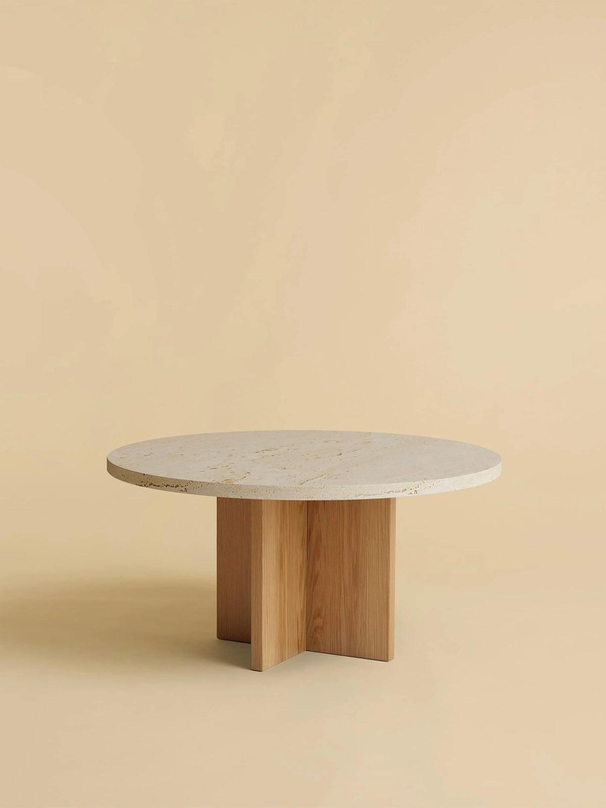 The Lebanto "Tinian" Coffee Table features a round marble top, artisan-crafted with a minimalist design and cross-shaped oak wood base, set against a beige background.