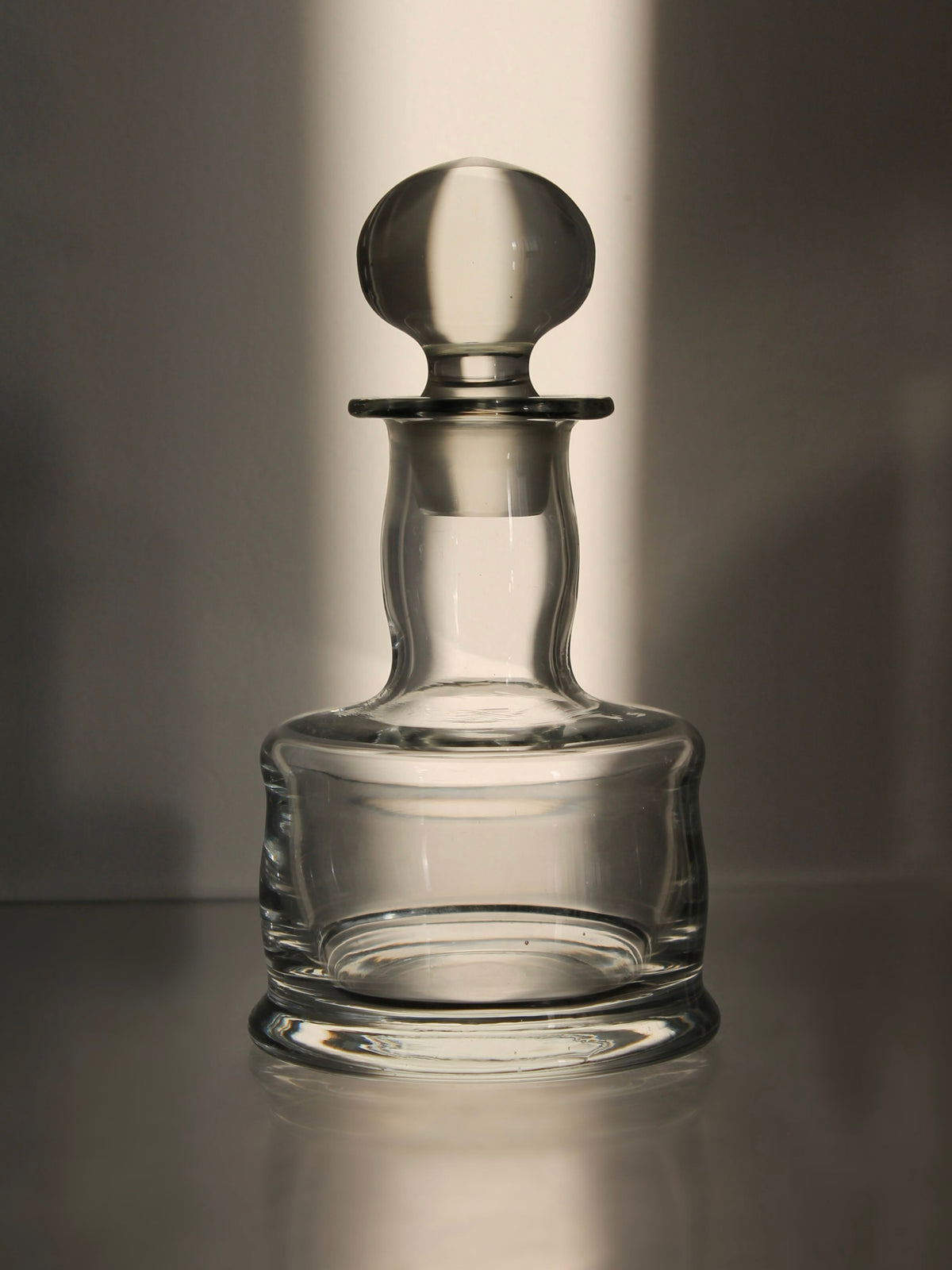 Clear glass mini decanter with rounded stopper and elegant base