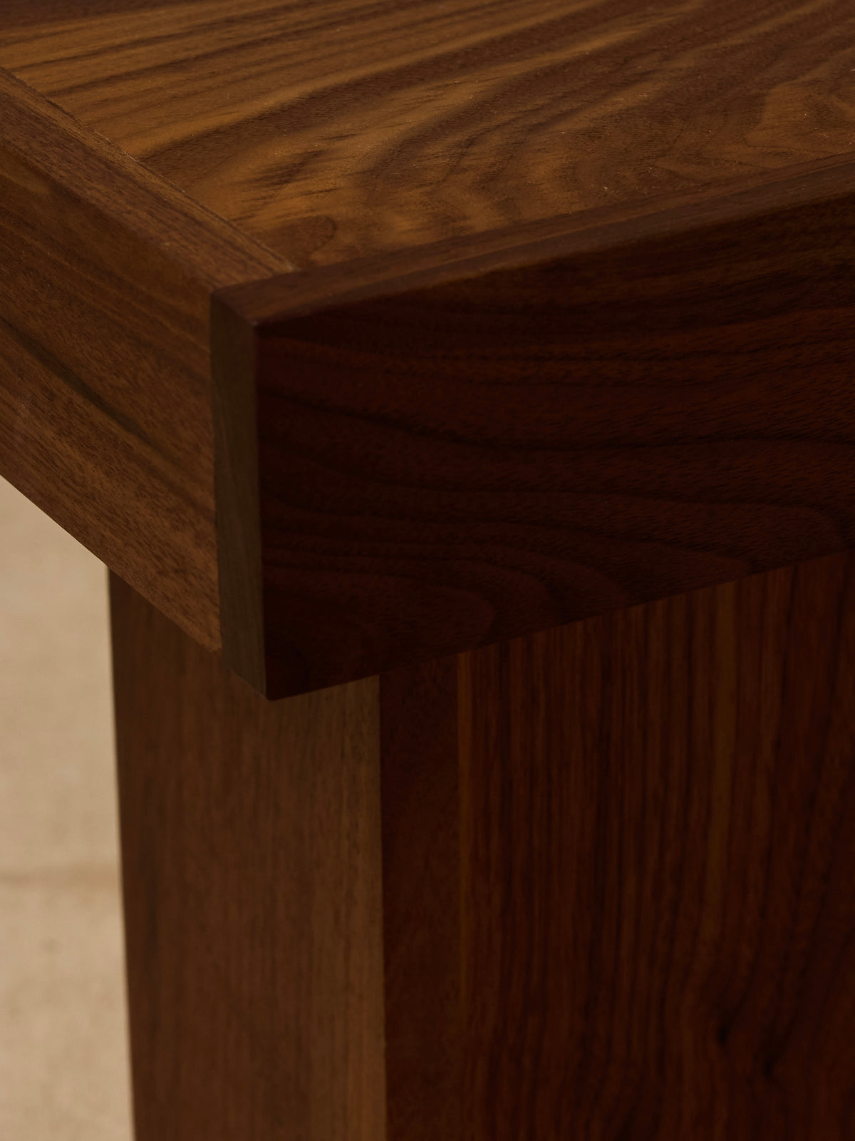 Close-up of the Jura Pedestal by Ah Um Design Studio, showcasing the rich brown wood grain, smooth finish, and detailed craftsmanship that highlight the natural texture of the handcrafted piece.
