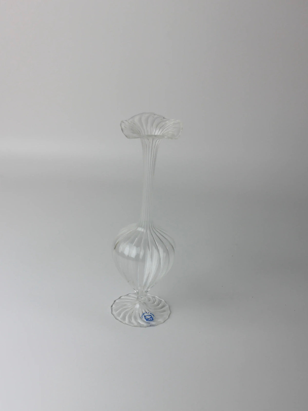 Against a plain white background, vintage blown glass Murano candle holders by Boga Avante Shop resemble flowers with fluted designs, bulbous bases, and narrow necks that flare at the top. A small sticker is placed near the bottom.