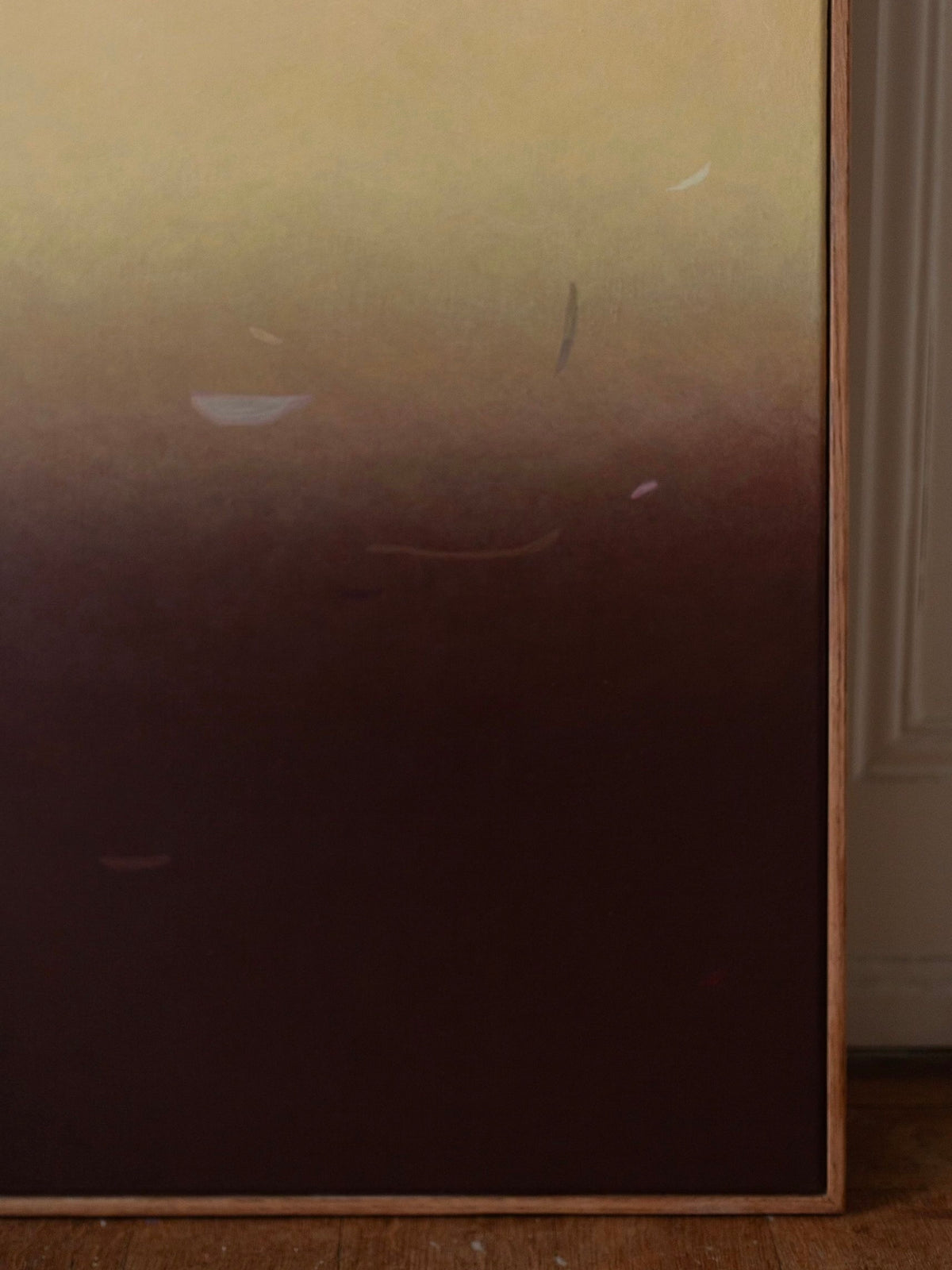The "Something(s) in the air", 2024 painting by Rebecca von Matérn is an acrylic on canvas artwork that showcases a gradient of earthy tones, transitioning from dark brown at the bottom to light beige at the top, with subtle abstract shapes. It is encased in an oak frame and elegantly displayed against a wall on a wooden floor.