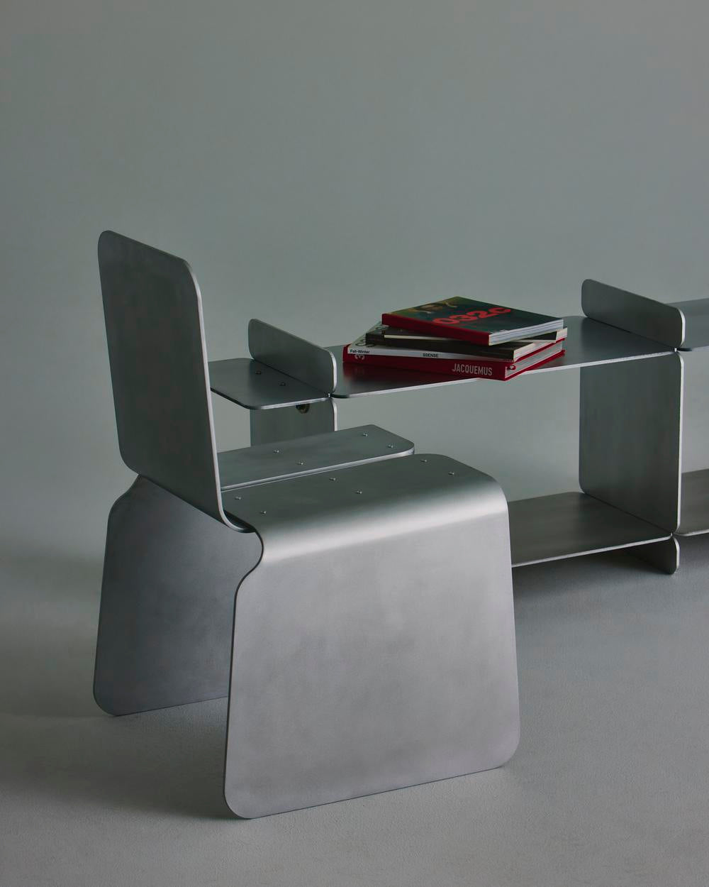 Modern glass console table with curved metal chair in minimalist setting