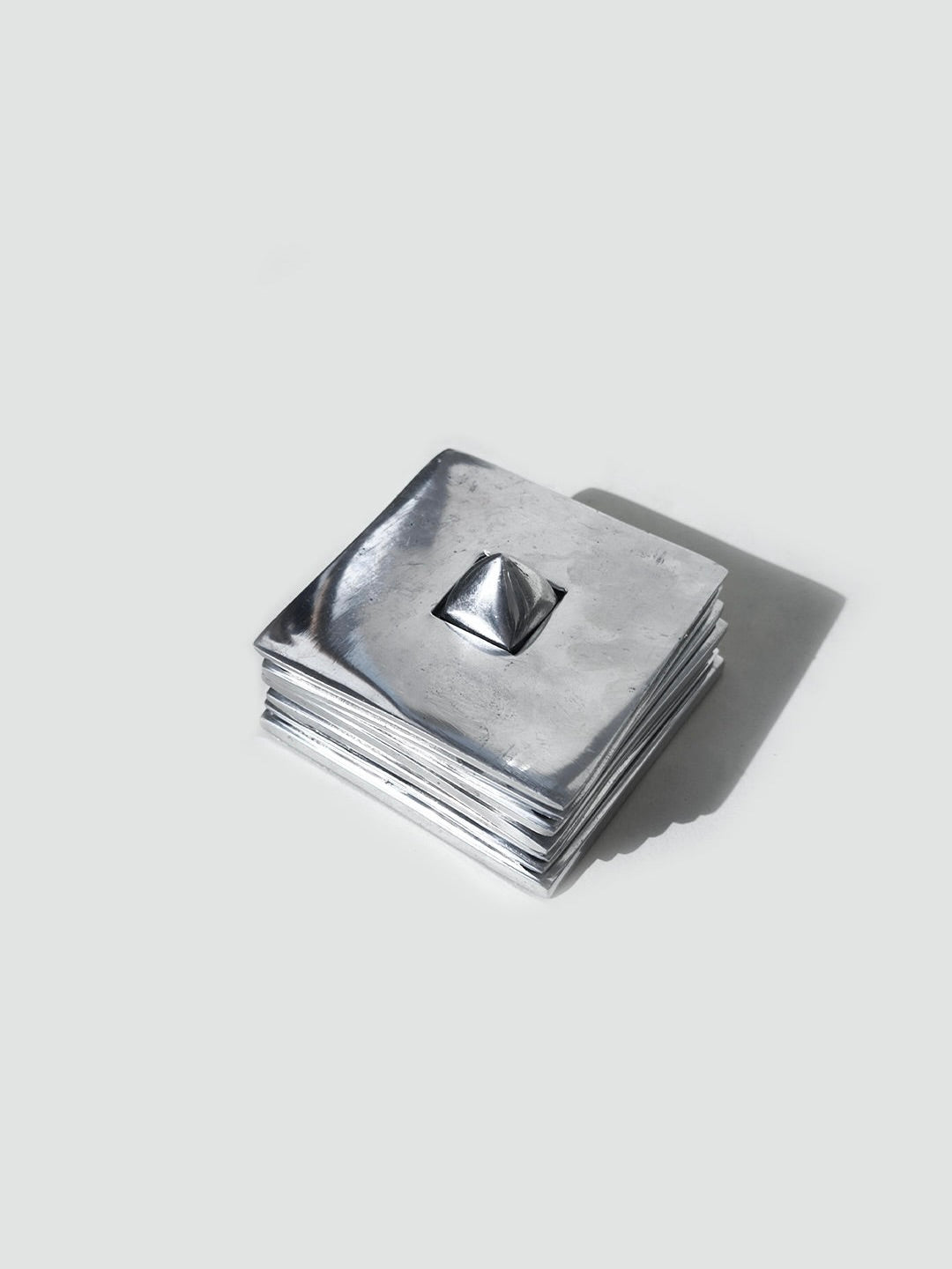 Set of 6 stackable silver metal coasters with pyramid center detail