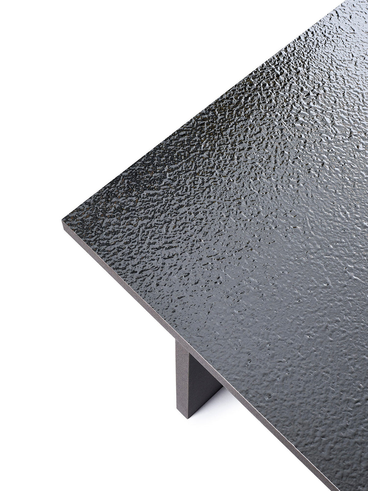 Close-up of a TEGET Mara Sister Coffee Table – Silver showing its black textured laminated tabletop with a glossy rippled finish and a visible corner. A rectangular dark gray leg supports its sleek modern design beautifully.