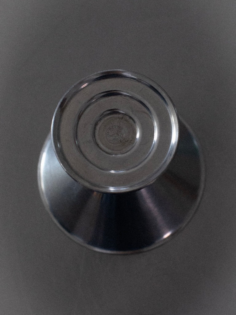 A set of six ice cream cups from the brand Out For Lunch is displayed in a top-down view. The background is gray, and the metal surfaces reflect light, giving the image a clinical and sterile appearance reminiscent of vintage stethoscope diaphragms and chest pieces made from tin in Norway.