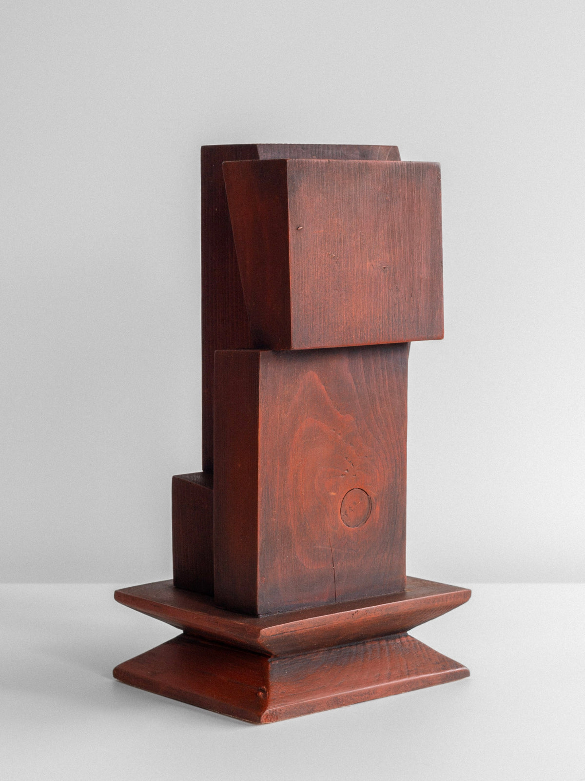 Displayed is the Vintage Cubist Sculpture by Atelier Boulogne, presented by Spigel. This geometric figural wood sculpture consists of variously shaped brown wooden blocks stacked in an abstract, vertical arrangement that evokes cubism. It rests on a flat base, contrasting with the plain, light gray background.