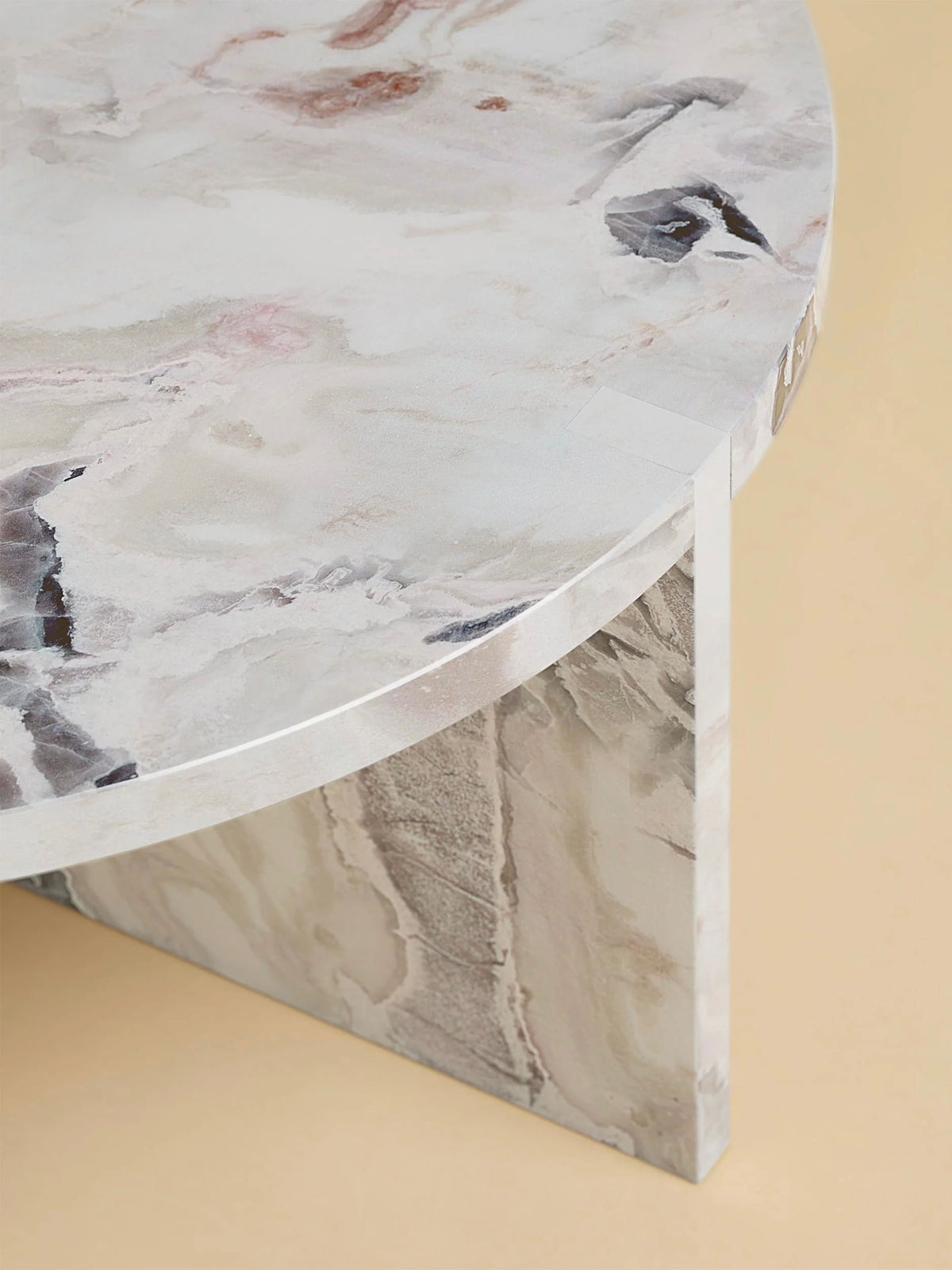 A close-up of the "Hashi" Coffee Table in Marble by Lebanto, featuring a circular beige and gray veined pattern. The tabletop showcases soft, natural swirls with a smooth, polished edge against a light tan background.