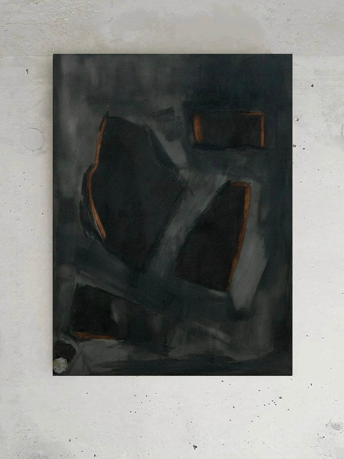 An artwork titled "Complex Hue's in G Minor" by Yeliza Gevorgyan, showcasing dark abstract forms highlighted with accents of orange on a textured gray background, elegantly ensconced in an Italian oak frame against a light gray wall.