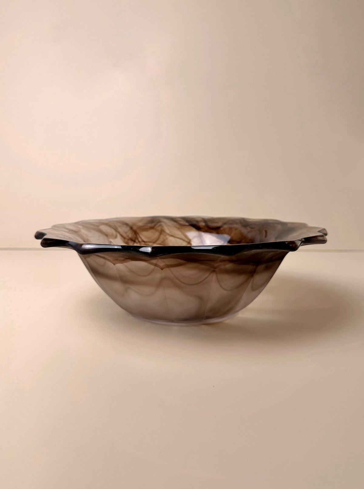 A shallow, smoky brown German Art Deco Cloud Glass Bowl with a pointed rim from around 1930 sits against a plain beige background. The swirled pattern within the glass gives it a marbled appearance, making this Dodo Vintage creation a stunning collectible bowl.