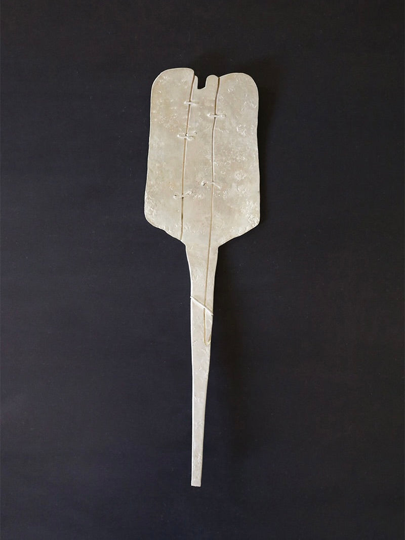 A metallic sculpture resembling a stingray against a dark background, crafted with a textured surface and apparent weld marks. Its long, narrow tail curves gracefully, evoking the elegance of the Silver Plated Cake Server by Rooms Studio. This unique piece was inspired by the artistic spirit of Tbilisi, Georgia.