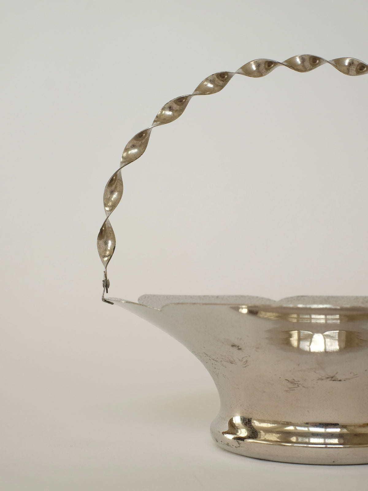 A close-up of septembre studios' Basket With Twisted Hand Barrel, showcasing its vintage charm against a plain background. The focus is on the elegant spiral design of the twisted handle and the polished surface of this decorative piece.