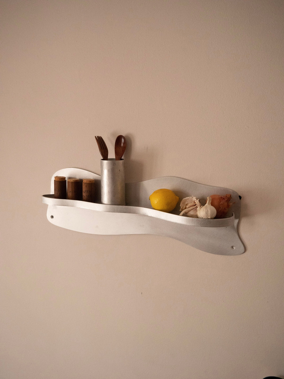 White wall-mounted kitchen shelf with spice jars and utensils