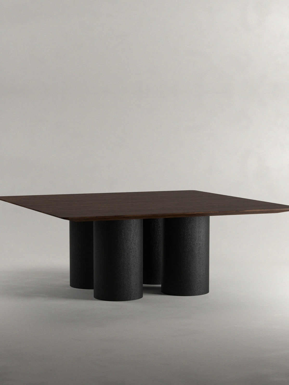 The 'Pier' Dining Table by Siete Studio features a contemporary square walnut tabletop on cylindrical black legs, set against a simple light gray background.