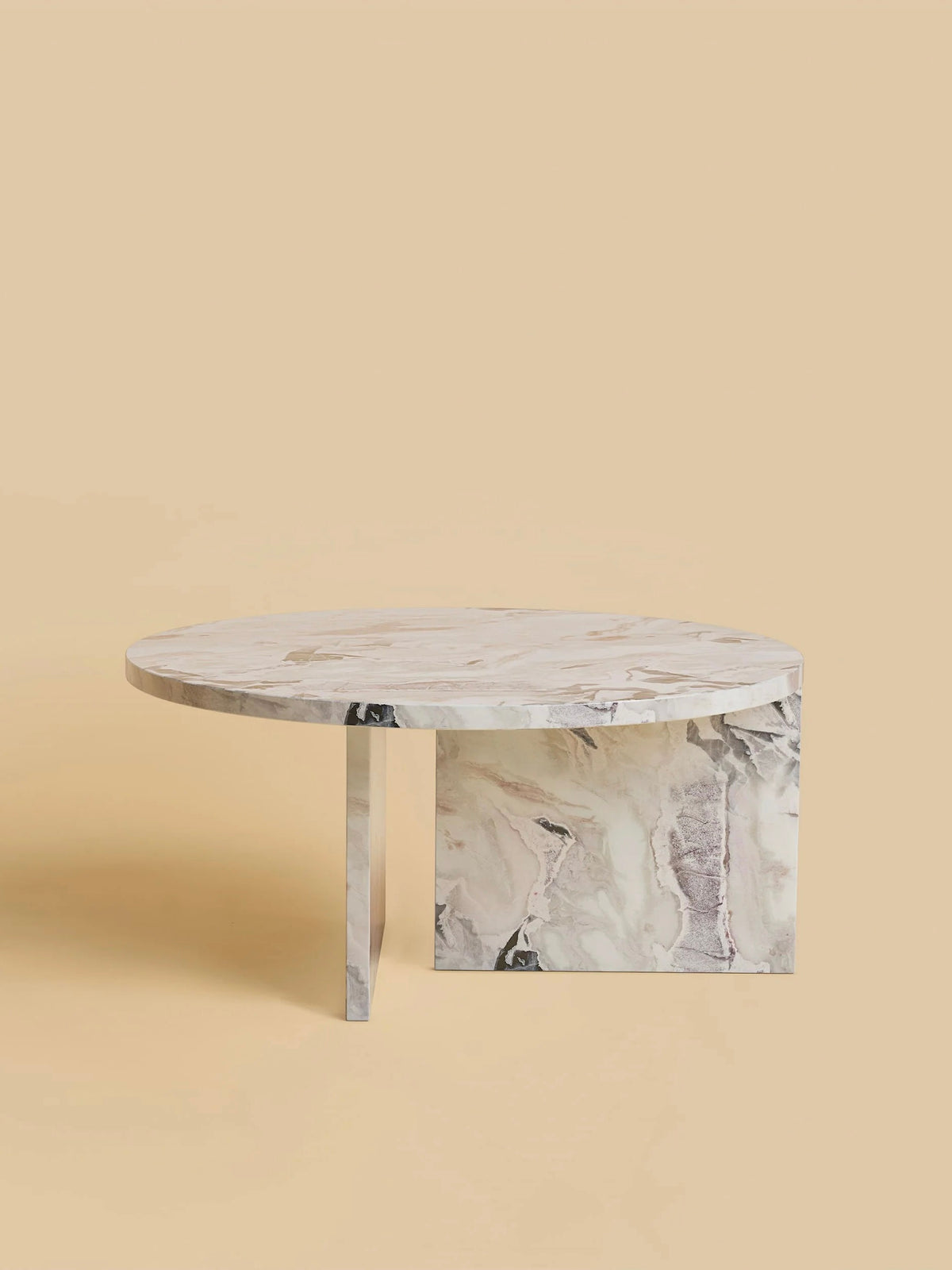 The "Hashi" Coffee Table in Marble by Lebanto stands against a beige background, showcasing a circular top with gray and white veining and an innovative half-circle base, offering a modern elegance reminiscent of fine travertine.