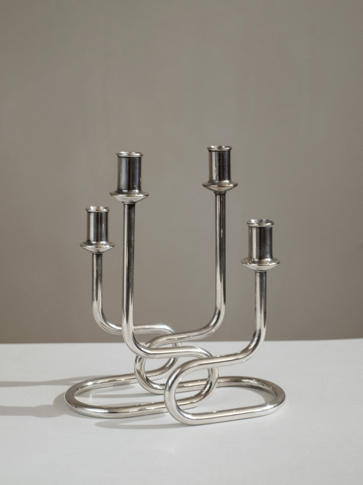 Modern silver metal candelabra with curved interwoven base design