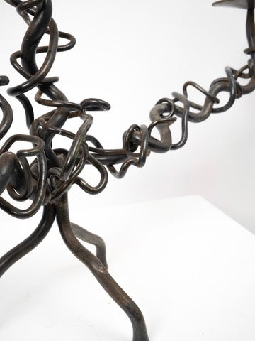 A close-up of the Tom Bogle Brutalist Iron Candelabra, featuring twisted and looping iron rods, displayed against a plain white background.