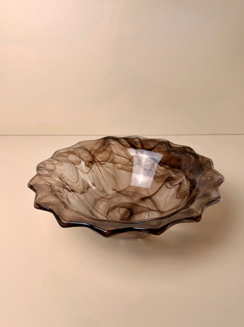 A round, shallow German Art Deco cloud glass bowl from around 1930 with a pointed rim. The Dodo Vintage bowl features a marbled pattern in shades of brown and beige, creating an elegant and artistic appearance. Set against a plain beige background, it makes for a stunning collectible piece.