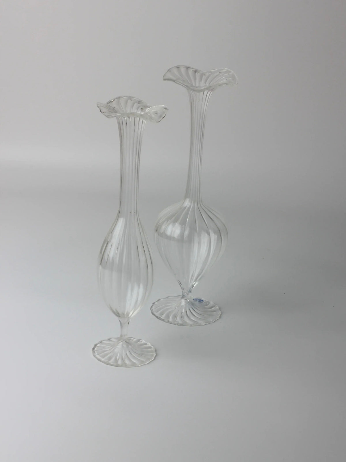 Two elegant Murano candle holders from Boga Avante Shop, with fluted tops and ribbed surfaces, stand side by side against a light gray background. Their slender, elongated shape gives them a classic, timeless style reminiscent of vintage blown glass.
