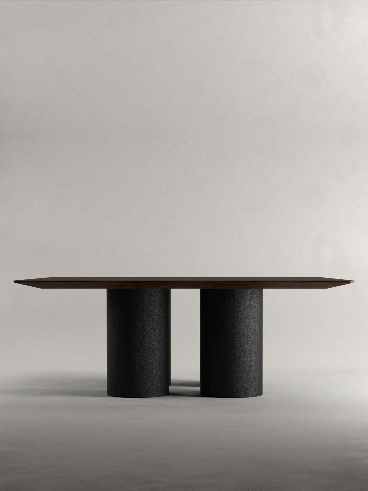 The 'Pier' Dining Table by Siete Studio has a dark walnut rectangular top and two large cylindrical black legs, set against a plain light gray background to enhance its modern, minimalist design.