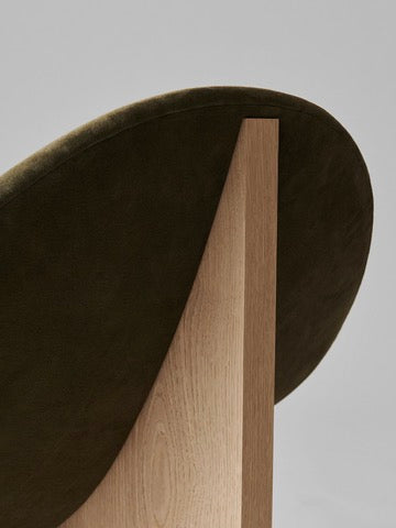 Close-up detail of Nido chair's curved olive upholstery and oak frame