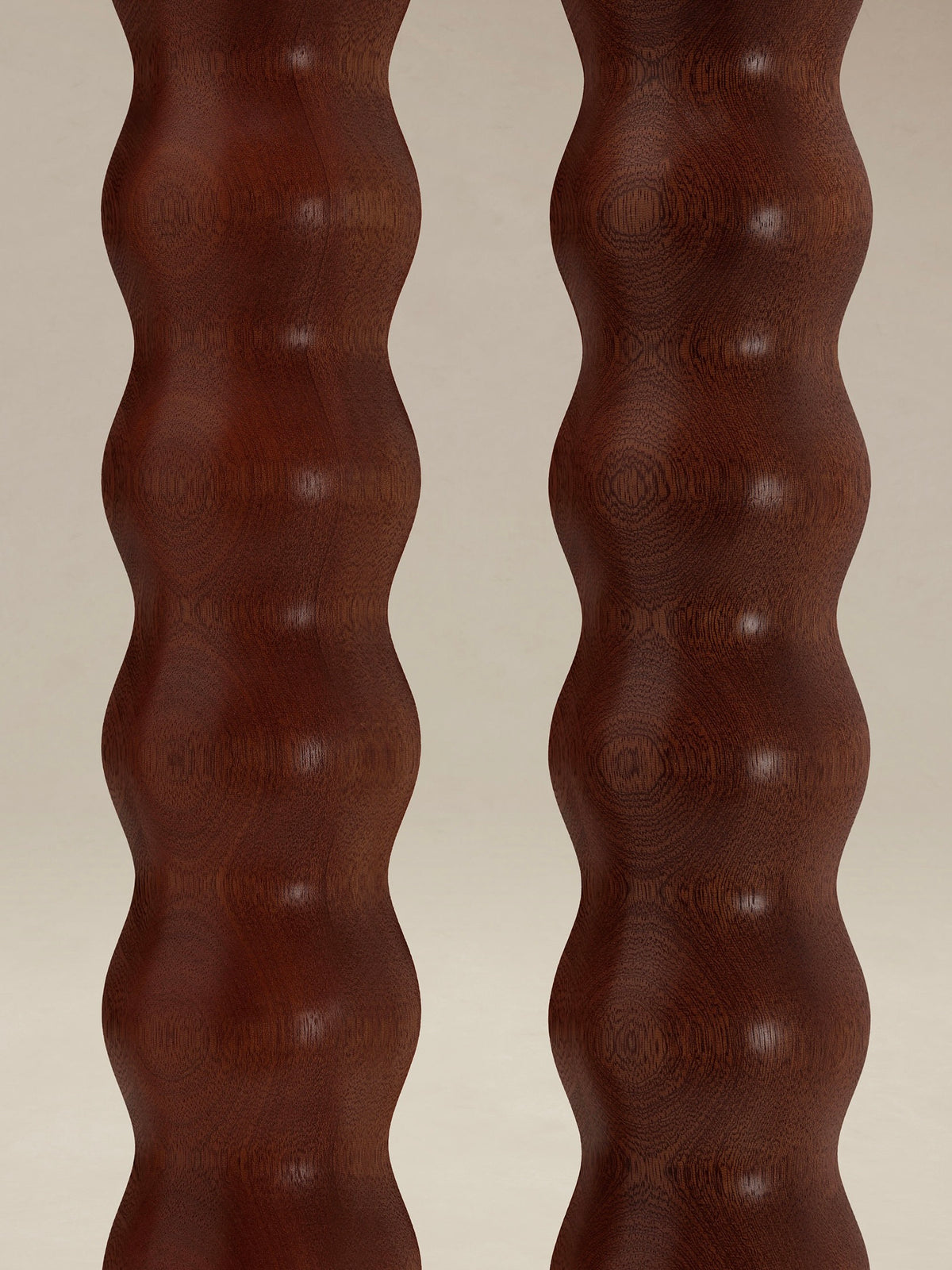 Close-up view of two wooden columns from AÈDE Studios' "Tougarine" Floor Lamp, featuring a wavy, textured surface. The rich brown wood and dual heads boast a glossy finish, beautifully showcasing its natural grain and undulating pattern.