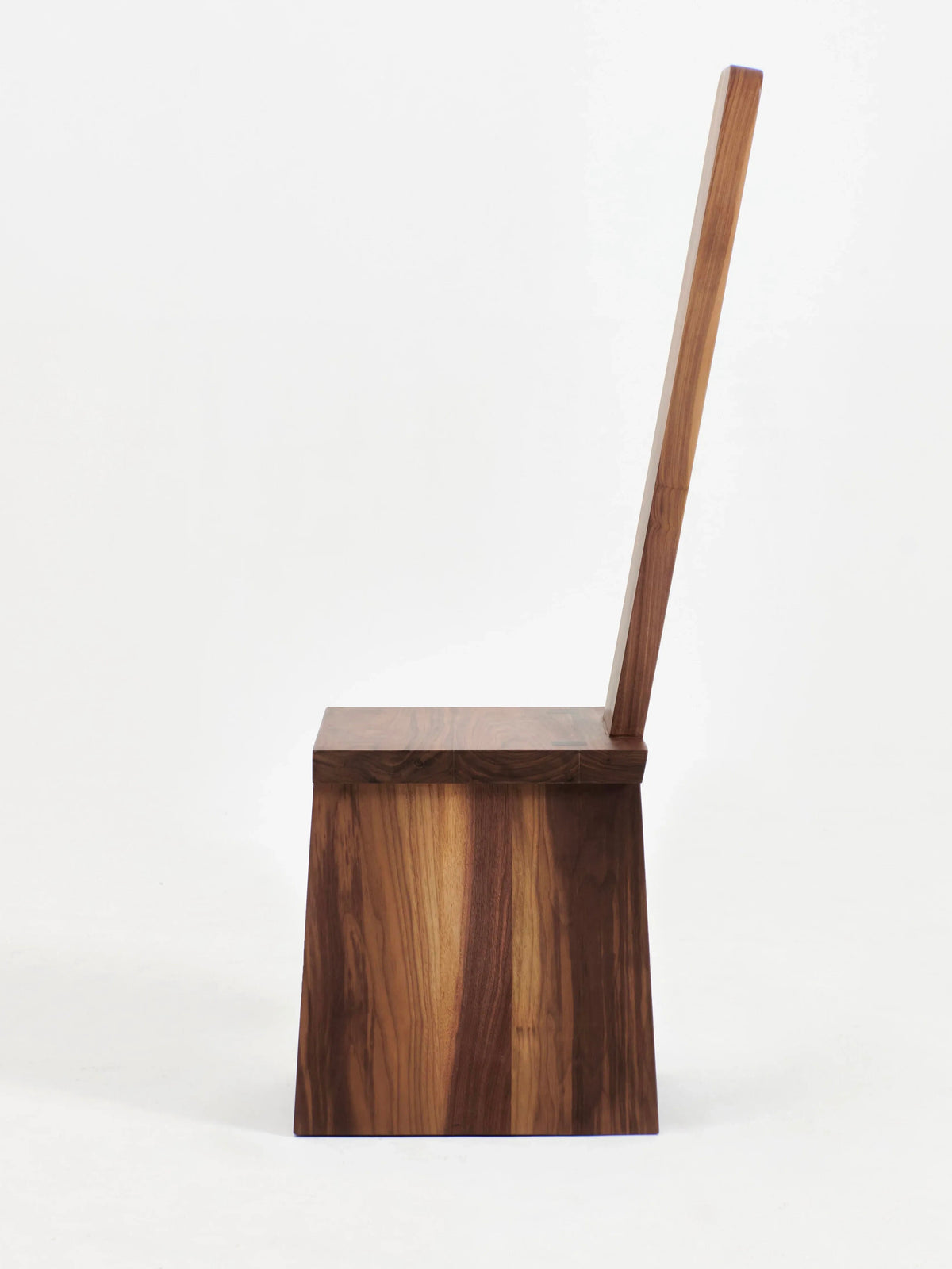 A modern, minimalist wooden chair from Project 213A, the Portugal Chair No 4, is displayed in a side view against a plain white background. The chair features a graphic backrest and a geometric, block-like seat and base, expertly handcrafted from rich walnut to highlight the natural wood grain.