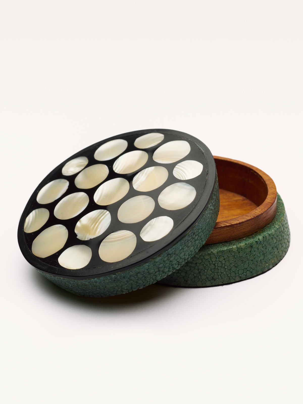 The Small Shagreen Pearl Box by Galerie MLS features a round green shagreen exterior, wooden interior, and removable lid adorned with circular mother-of-pearl inlays in a grid pattern. The slightly tilted lid reveals the box’s elegant inside.