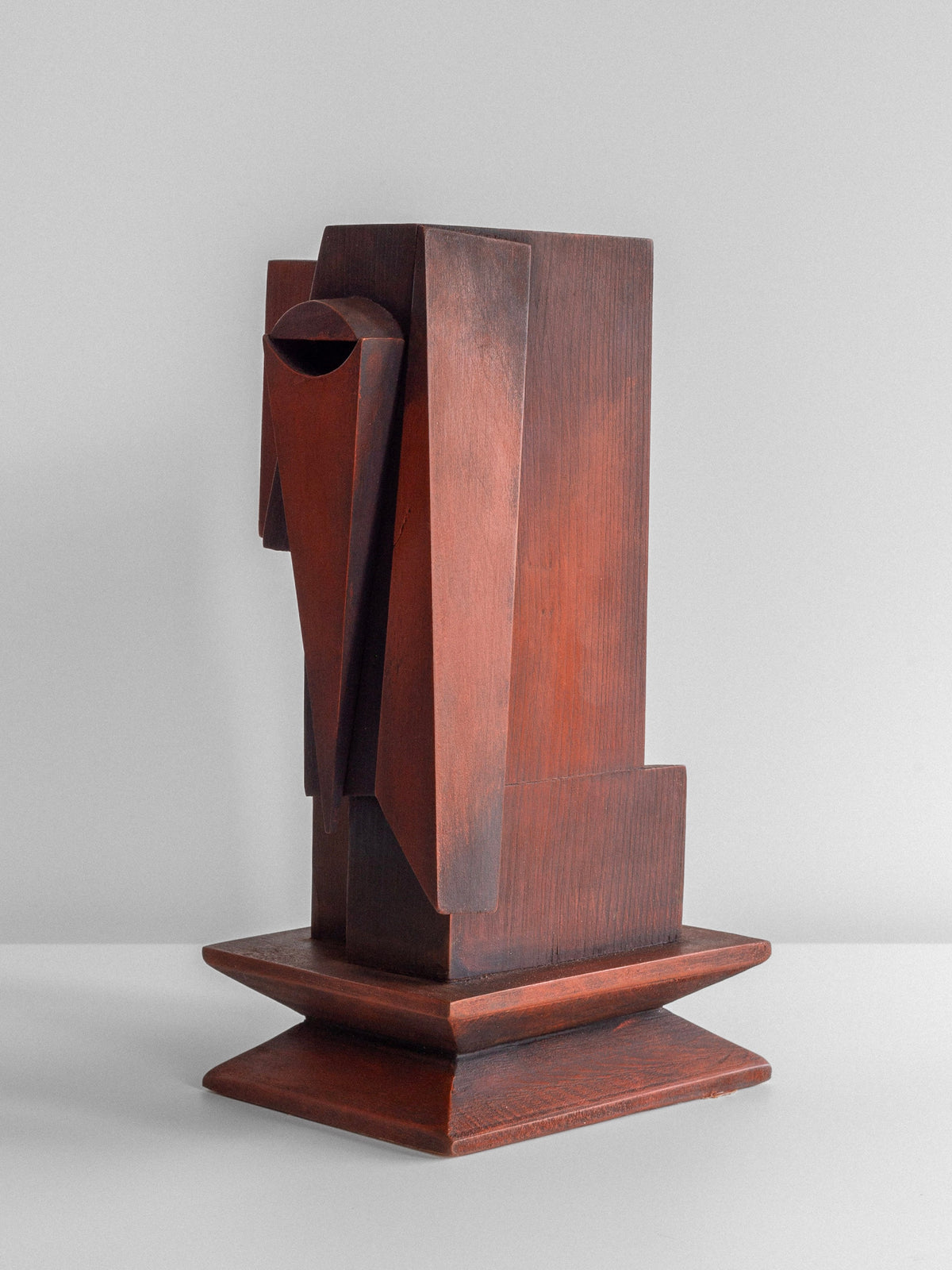 The Vintage Cubist Sculpture by Atelier Boulogne, offered by Spigel, showcases a wooden abstract design with angular geometric shapes, including a prominent triangular form extending from the center. It stands on a square base against a plain white background and features wood with a smooth finish and reddish hue.