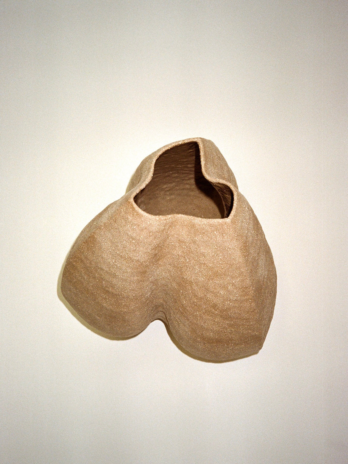 Growing Vase n.2 by Aiste Bagdonaite is a beige, abstract hand-built stoneware vase with a textured surface and asymmetrical opening, showcasing organic shapes and artisanal craftsmanship against a light background.
