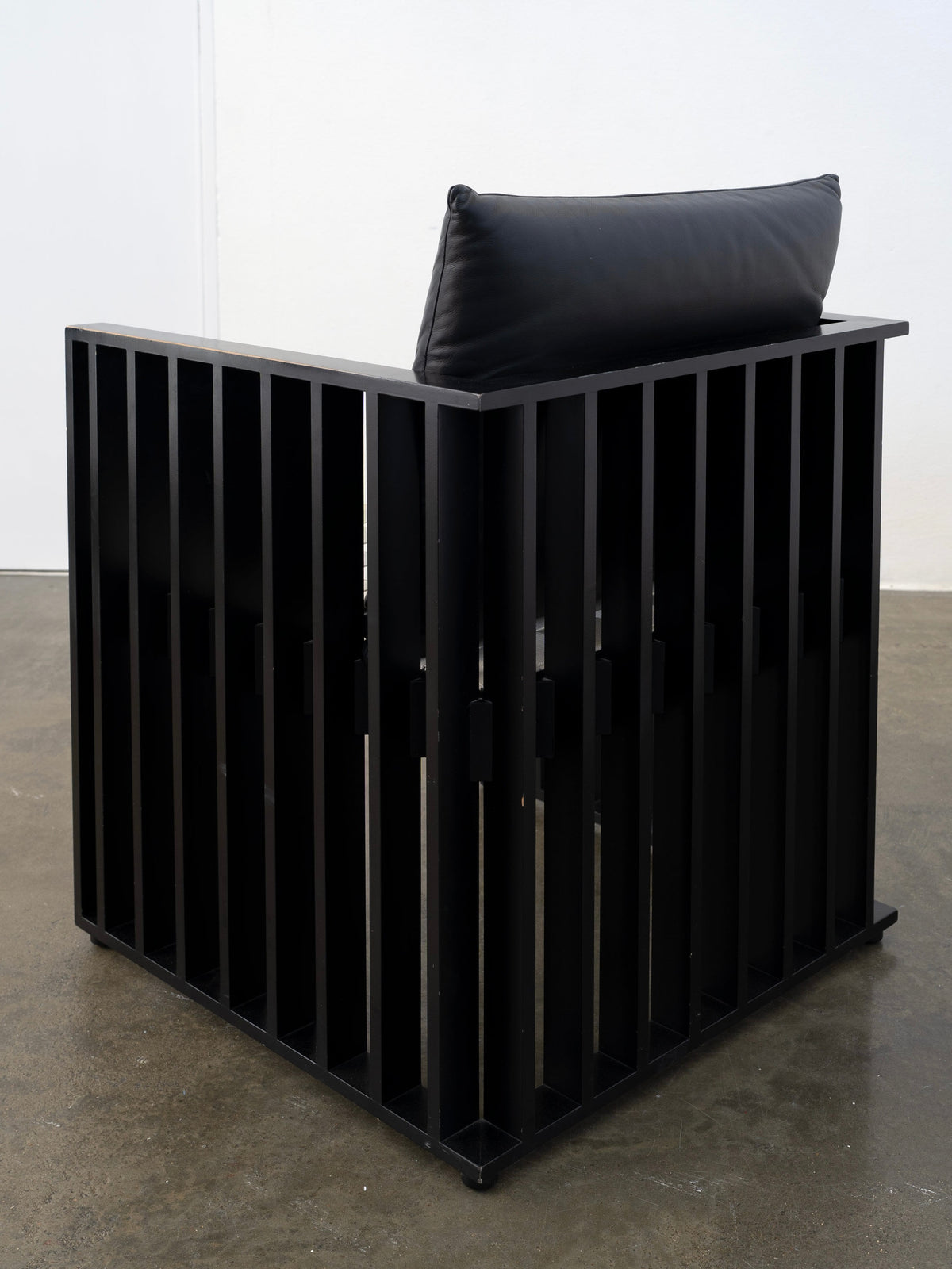 Black metal slatted corner chair with dark cushion by Hoffmann