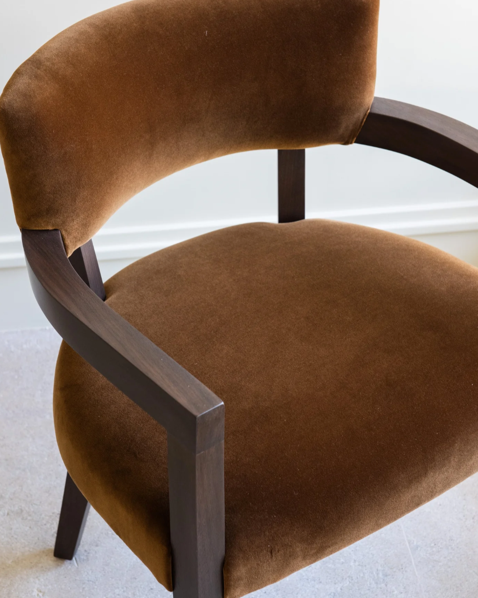 Close-up detail of Hillcrest dining chair's curved brown velvet upholstery and dark wood frame