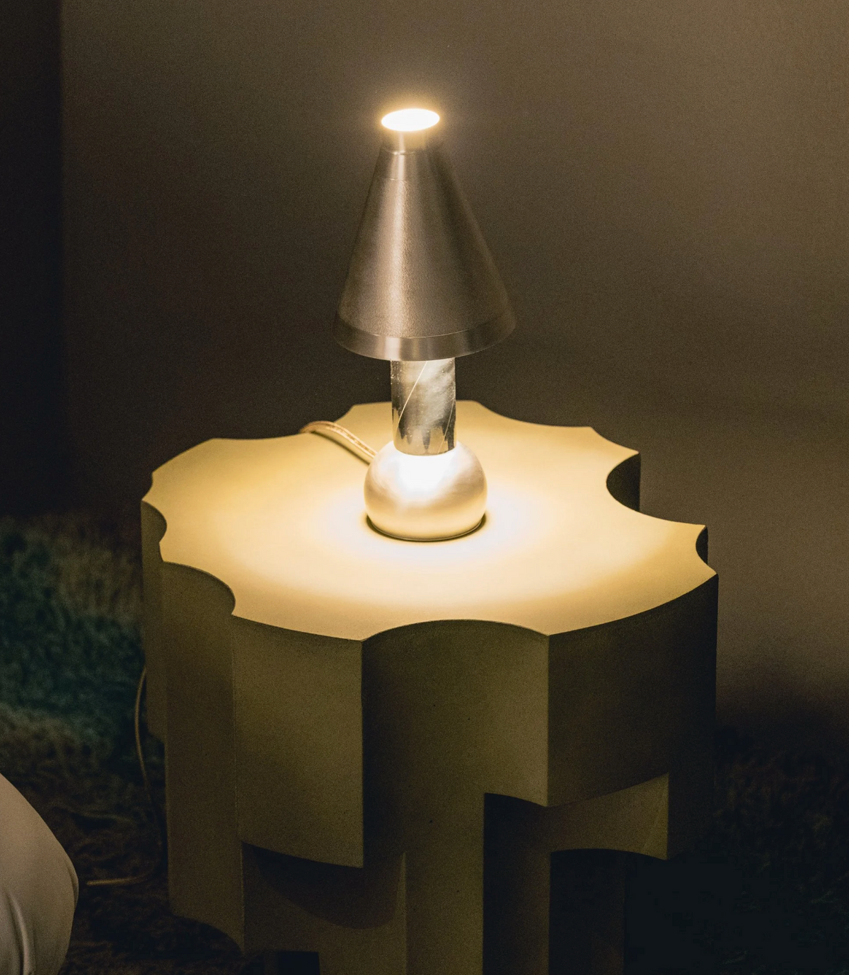 Metallic cone table lamp on sculptural wavy side table, lifestyle view