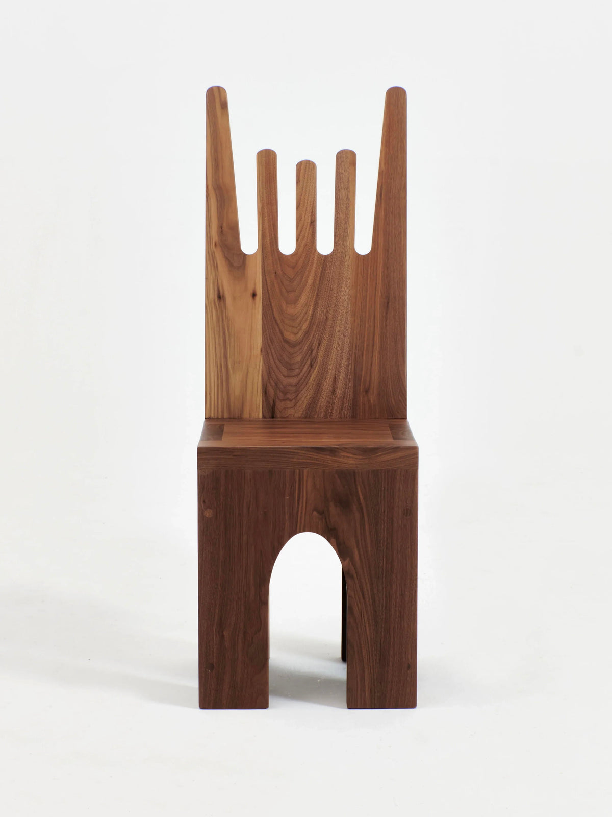 The Portugal Chair No 5 by Project 213A is a wooden chair with a unique design, featuring a high backrest with five vertical slats of varying heights that resemble fingers. Its solid walnut seat boasts a minimalist rectangular shape, complete with a small arch cut out from the lower front.
