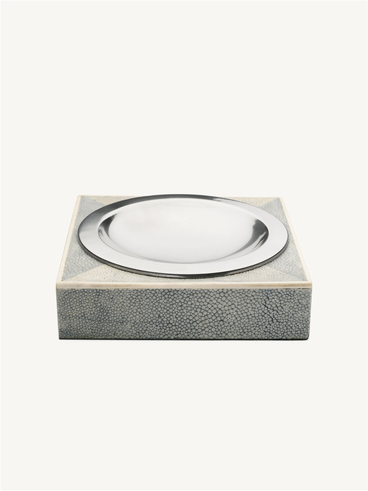 The Shagreen Ashtray by Galerie MLS is a square, gray piece with a textured finish and a round, shiny silver dish set into the top, shown on a plain white background.