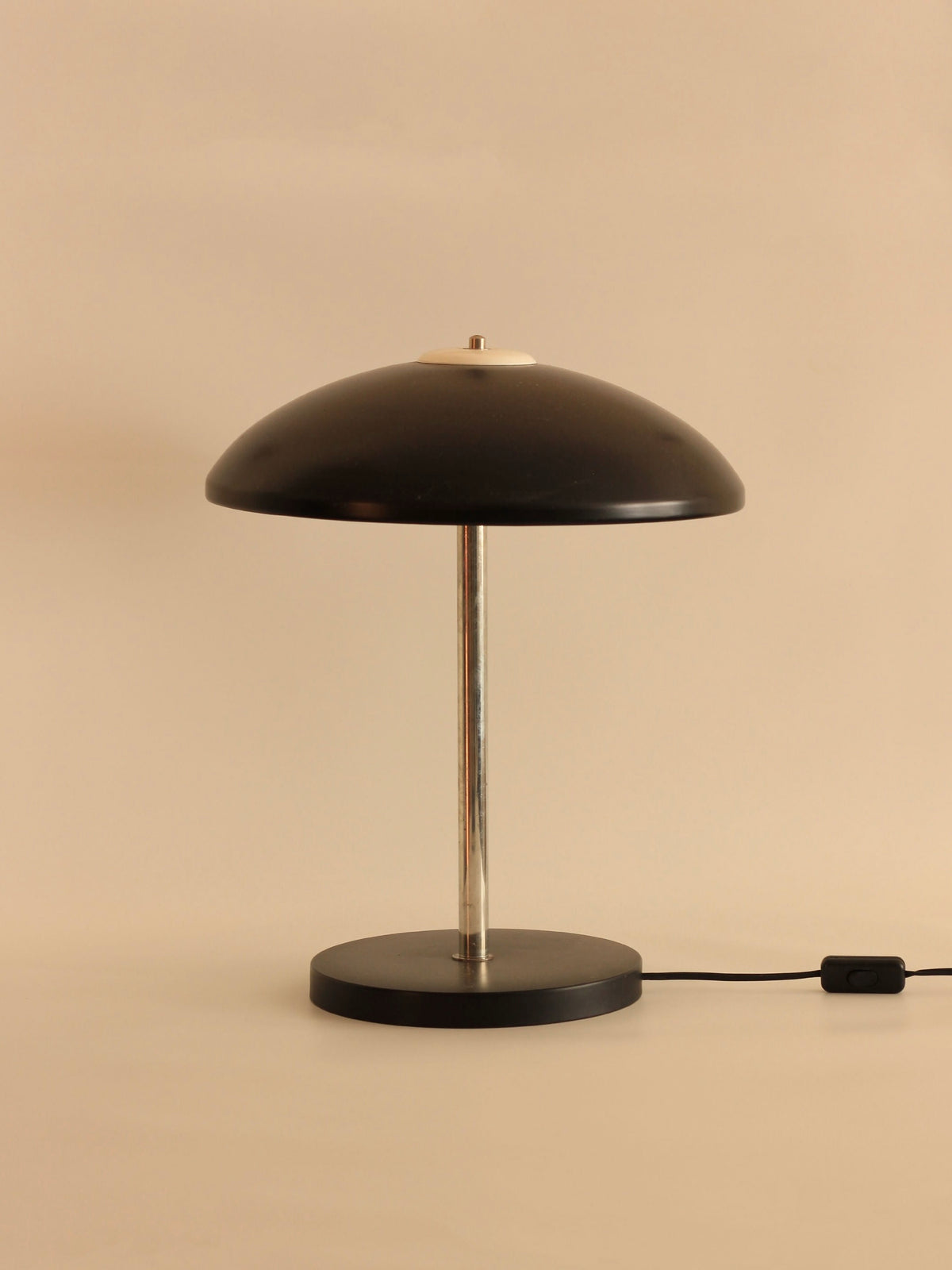A minimalist German Mushroom Table Lamp by Boga Avante Shop, featuring a black, dome-shaped shade and a sleek chrome stem on a round black base. The lamp includes a power cord with an attached switch and is set against a plain beige background, making it an ideal addition to mid-century modern interiors.