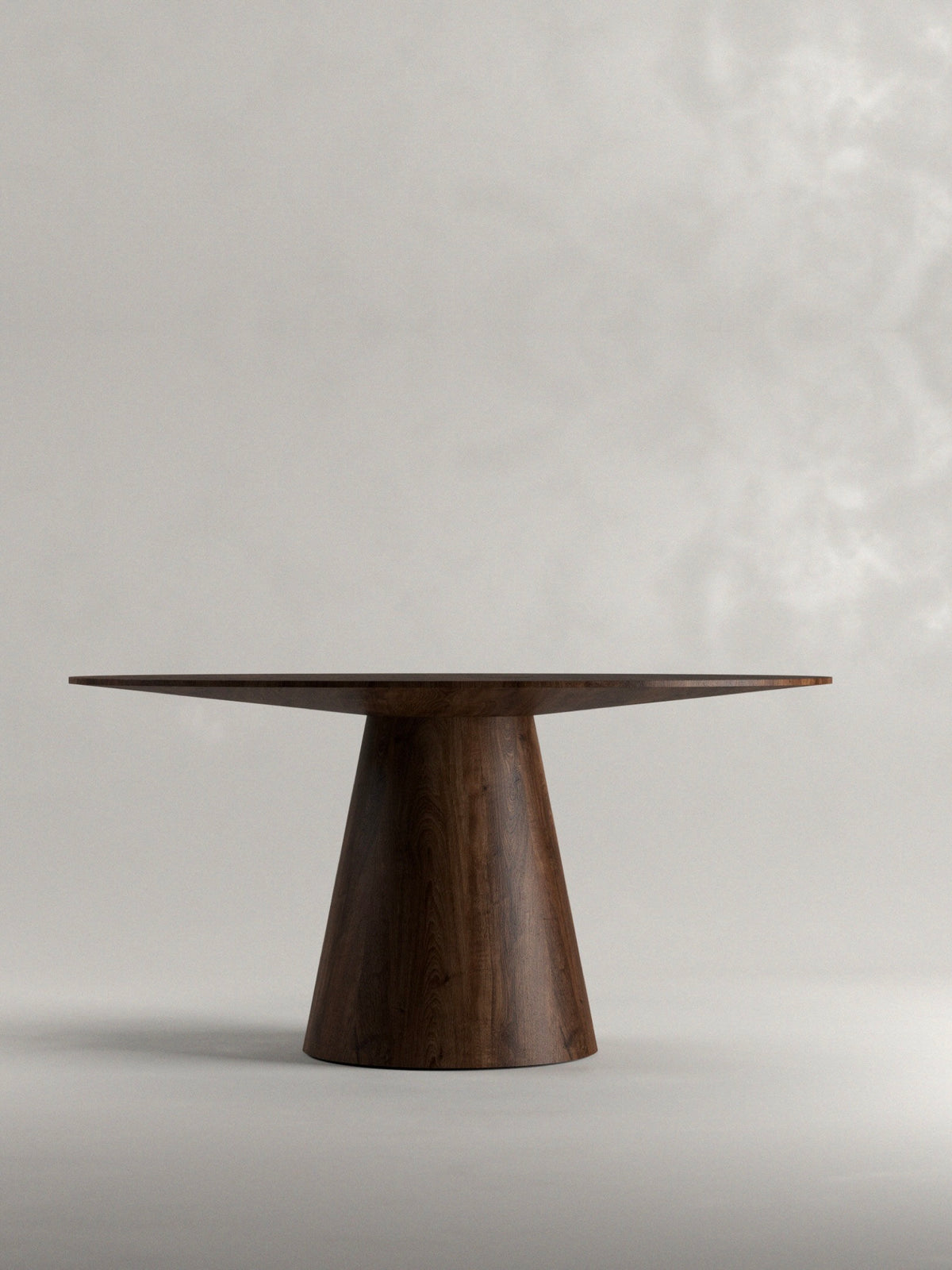 A handcrafted 'Totem' Dining Table by Siete Studio, featuring a round top and conical base in solid walnut, stands against a plain background casting a soft shadow. Its smooth finish enhances the natural wood grain beautifully.