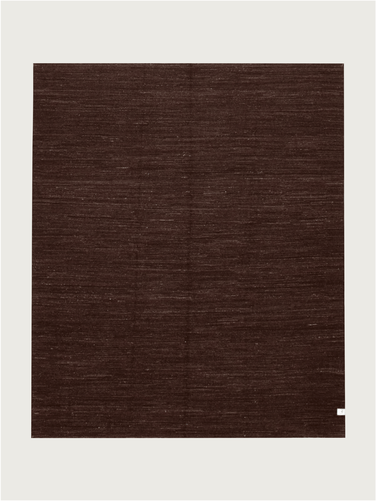 A unique large square Flatweave Rug in Walnut (244 x 292 cm) by catalog:three, set against a light background. It features a subtle weave pattern with a small white label in the bottom right corner, showcasing its wool hand-woven kilim craftsmanship.