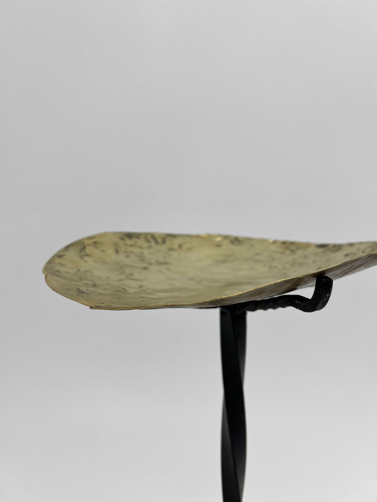 Brass candleholder detail showing hammered texture and curved hook