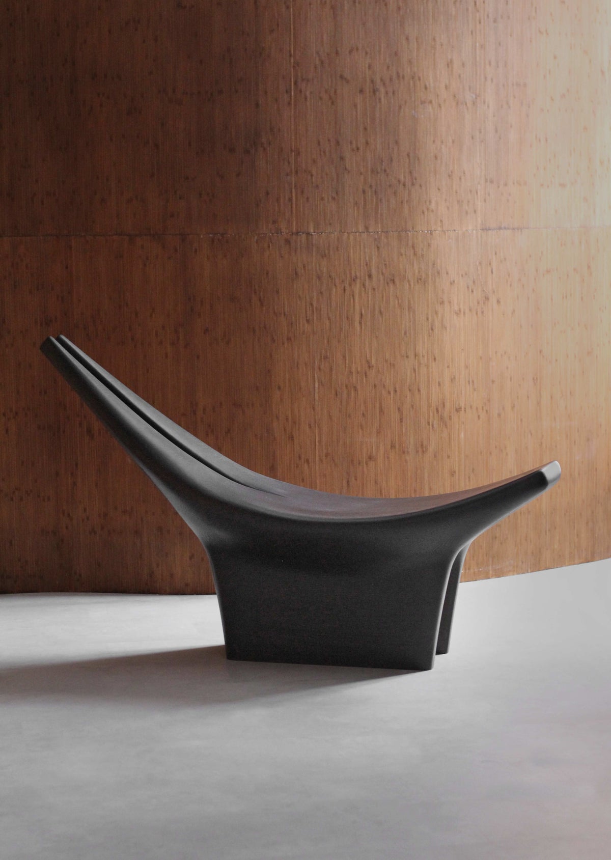 Dym Lounge Chair — angled view against wooden wall