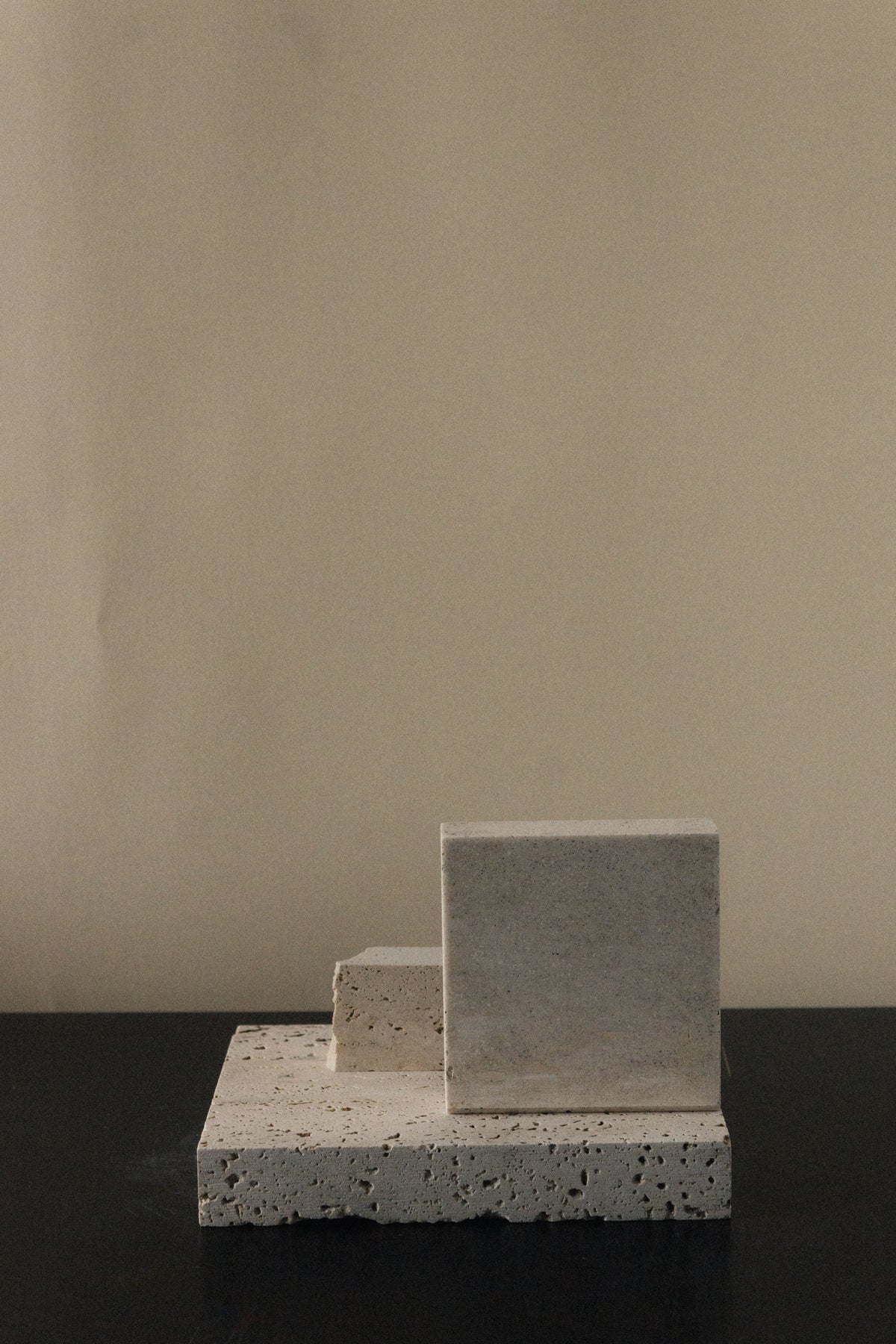 Monument II - Handmade Travertine Marble Bookstand — side angle showing textured surface on dark table