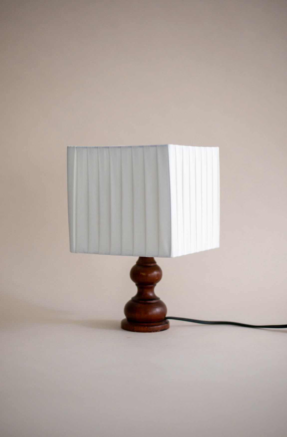 Modern table lamp with pleated white shade and turned walnut base