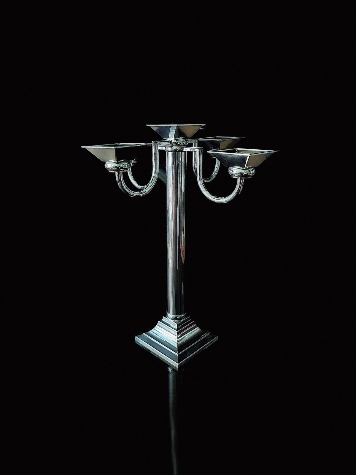 A Silver Plated Art Deco Candelholder from the 80s by Dodo Vintage with a sleek, modern design stands on a reflective black surface against a plain black background.